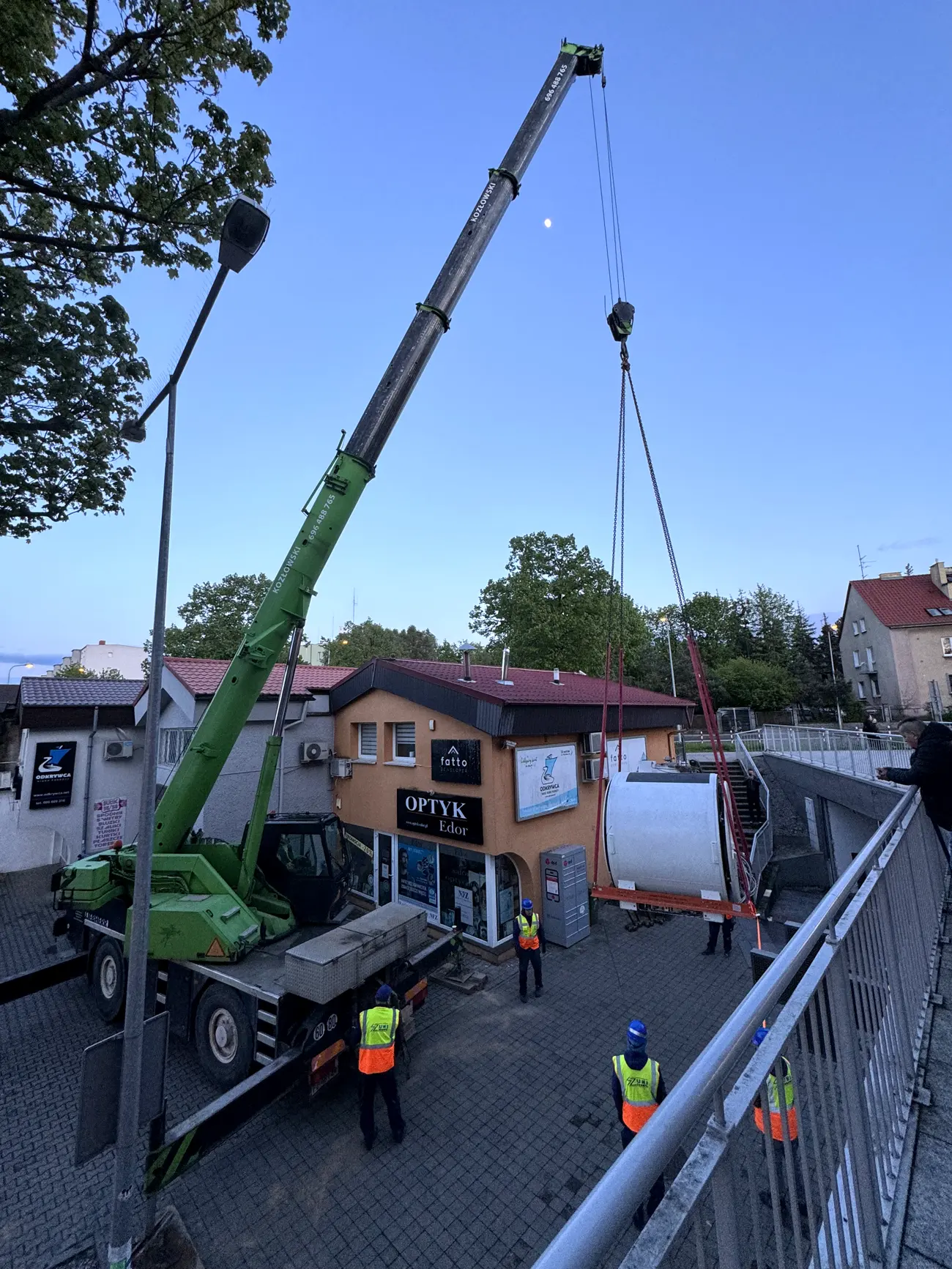 Mobile crane lifting an air handling unit in the evening