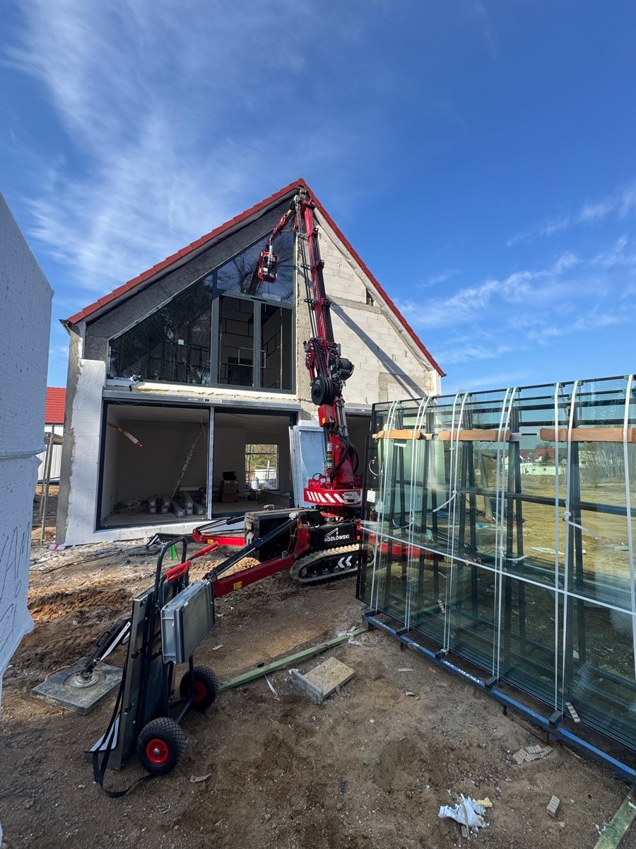 Compact crane fitting gable glazing in a new house, glass racks in the foreground