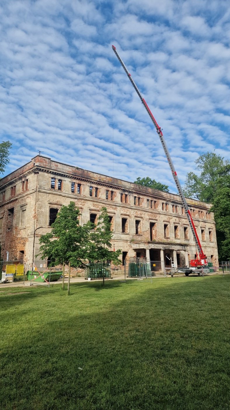 Truck mounted crane reaching over a historic palace facade