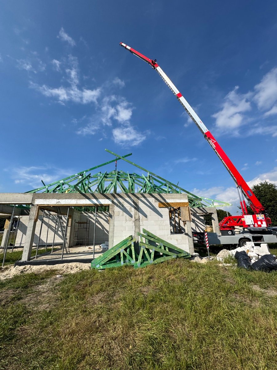 Truck mounted crane setting roof trusses on a new house