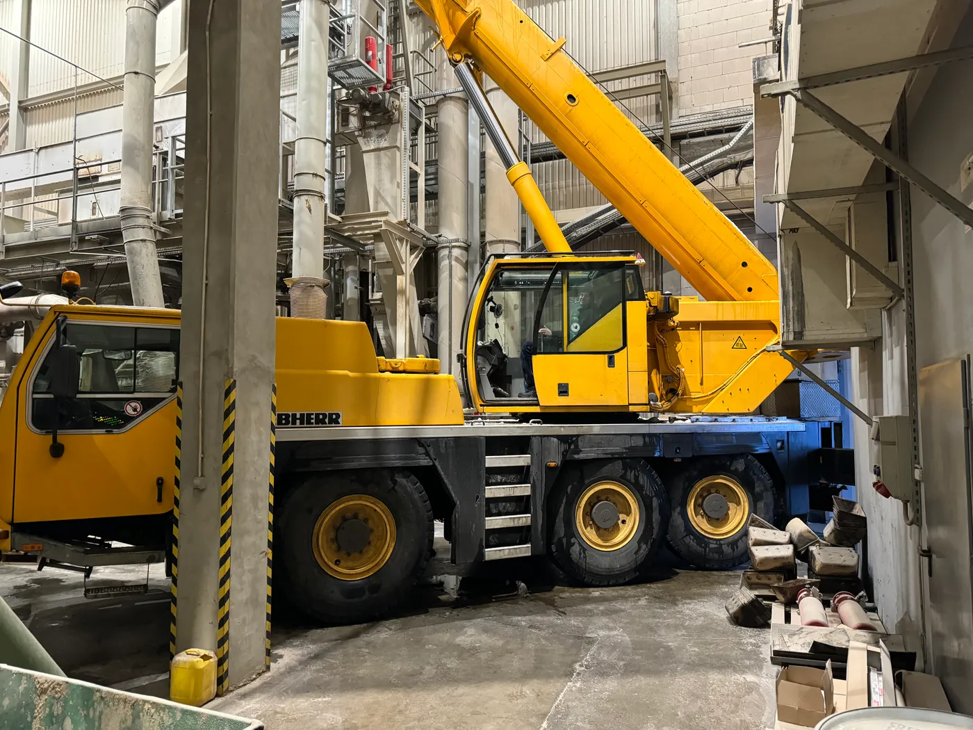 Mobile crane assembling steel structure inside an industrial hall